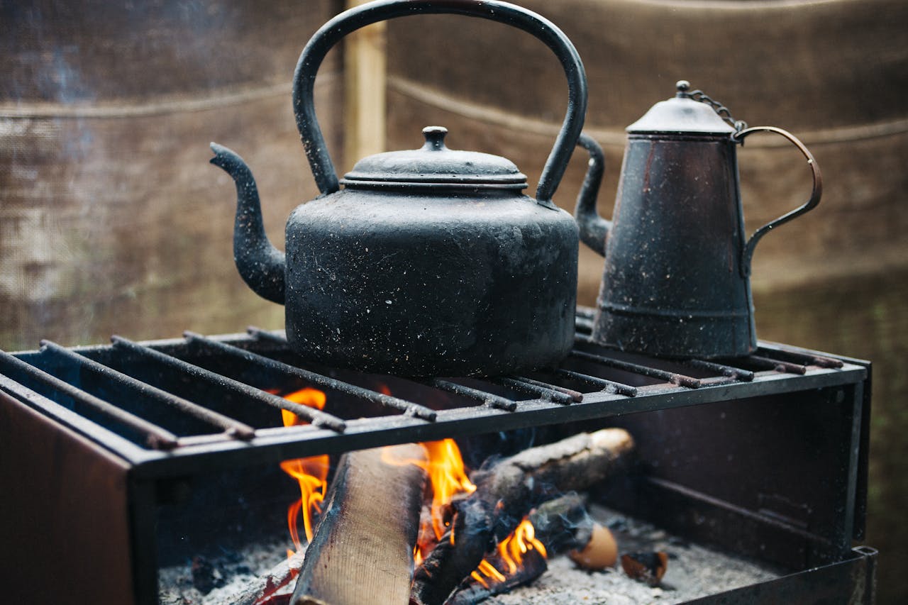 A vintage iron kettle over an open flame, exuding a rustic and warm outdoor ambiance.